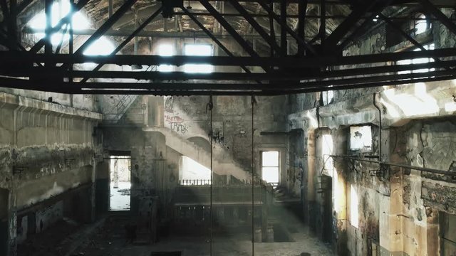 Interior motion real time shot of a long abandoned and partly demolished industrial factory in Greece.Sun light creeping through holes in the wall.