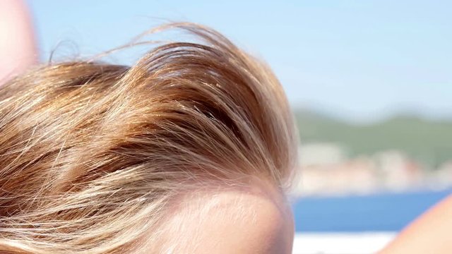 Girls hair waving in the wind on beautiful sunny day. She is repairing her hair with her hand. Filmed in slow-motion hd.