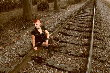 Junge Punk-Frau sitzt auf Schienen 