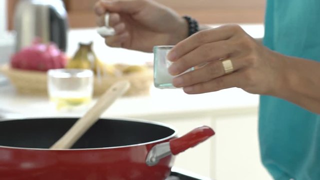 Woman mixing ingredients on frying pan and adding salt, steadycam shot
