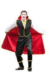 halloween, carnival, performance concept. on white background isolated figure of young man that has extremely excited face dressed like vampire, he is holding his robe like the wings of bat