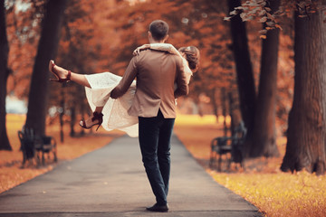 Obraz premium Newlyweds groom and bride walking in autumn park