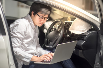 Young Asian Engineer or Architect working with laptop computer while sitting in his car. Mechanical engineering and building construction concepts