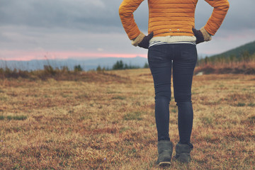 Woman walking on a mountain meadow in sunset / sunrise time.