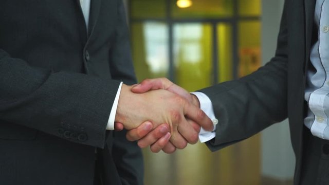 Two business men shaking hands slow motion