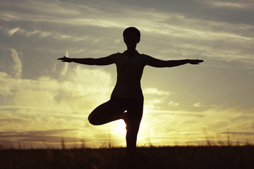 Fototapeta na wymiar Silhouette of a young girl yoga pose sunset sport