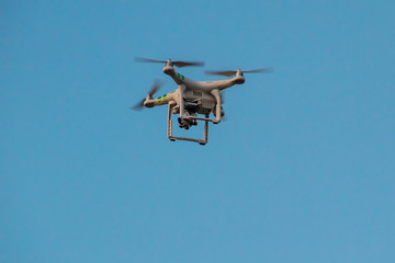 Naklejka na ściany i meble Drone with the camera hovering in blue sky
