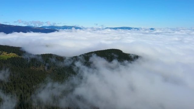 Aerial view: Flying above misty clouds. Beautiful landscape of mountains. Fog covering mountains. Nature concept. Birds eye view