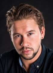 Fototapeta premium Smart serious young man posing on a black background