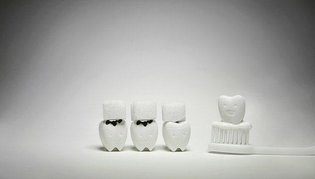 Cubes sugar and Decayed tooth Model and Happy Emotion Teeth Model on White Toothbrush and Toothpaste, if Eat a Lot of Sweet will be Decayed tooth and If Brush the teeth every day will be good healthy