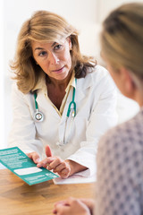 Doctor Discussing Leaflet With Female Patient
