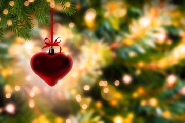 weihnachtsdeko, hängendes rotes Herz an tannenzweigen, festlicher hintergrund