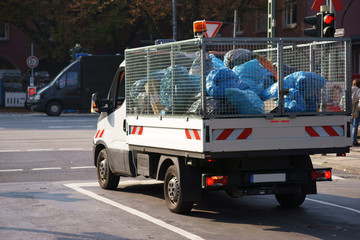 Müllabfuhr / Ein kleiner Transporter mit vergitterter Aufladefläche transportiert Müllsäcke.