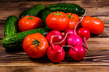 Ripe tomatoes, radish and cucumbers on wooden table