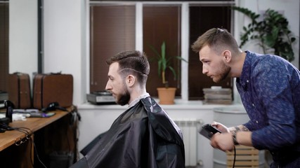 Barber stylist making hair to male customer sitting in barbershop