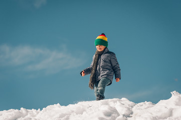 Fototapeta na wymiar Little boy climbing the snow hill, winter vacation with children. Image taken in Valais, Switzerland