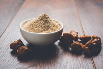 Asafoetida cake and powder or Hing or Heeng which is an important ingredient in Indian food recipes with big wooden spoon and mortar, selective focus