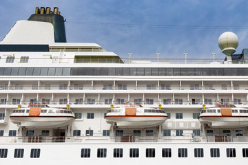Cruise ship side with lifeboats, windows, stack, radar and blue sky. Cruise liner side close up...