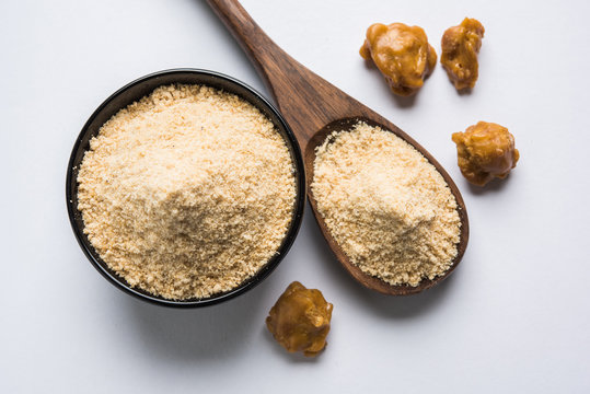 Asafoetida cake and powder or Hing or Heeng which is an important ingredient in Indian food recipes with big wooden spoon and mortar, selective focus