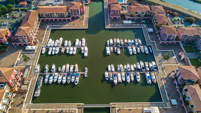 Aerial view of marina with boats and yachts on port of modern residential district from above
