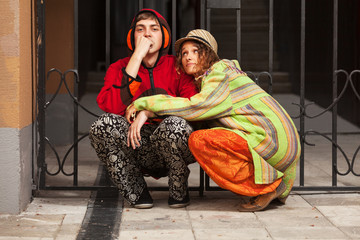 Young fashion hipster couple sitting at the iron fence