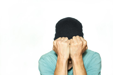 Young man trying to cover his eyes with hat while he suffering from strong migraine headache pain attack isolated on white background