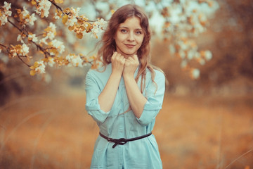 young happy woman walking in an apple orchard in the spring flowers white