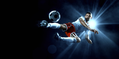 Soccer player performs an action play on a dark background. Player wears unbranded sport uniform.