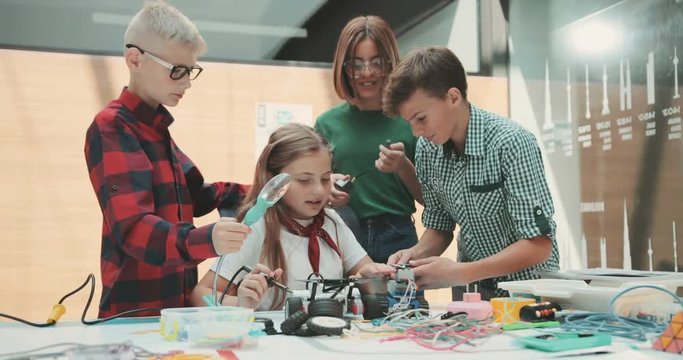 A team of children is working in the office. Discuss new toy development. Pour a machine. Feel happy. Contemporary design. Modern toys. Shot on RED Epic Camera.