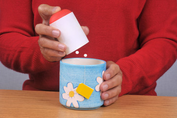 Personne mettant des sucrettes dans sa tasse de thé