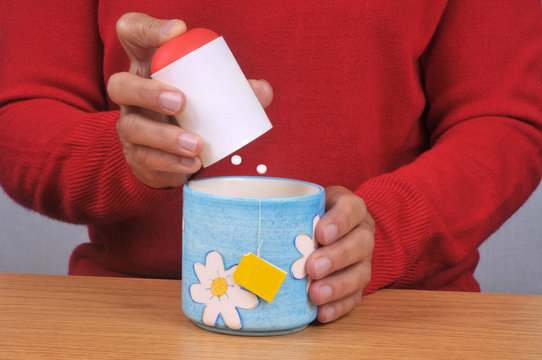Personne mettant des sucrettes dans sa tasse de th&eacute;