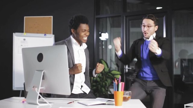 Two Successful businessmans juming and raising hands in the office