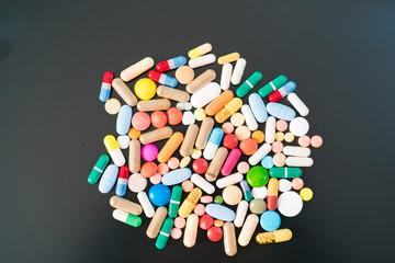 Multicolored pills and capsules on a black background