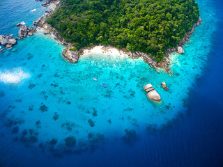Top aerial view of isolated beautiful tropical island with white sand beach, blue clear water and granite stones. Also top view of speedboats above coral reef. Similan Islands, Thailand. © Marina