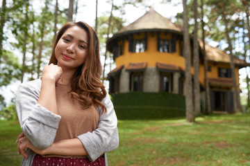 Obraz premium Waist-up portrait of smiling Asian girl posing against the background of her countryside house