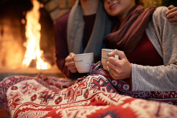 Loving couple drinking hot tea near fireplace on Christmas Eve