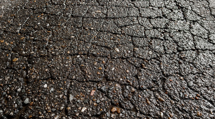 Wet cracked asphalt road after the rain. Asphalt perspective. Asphalt background. Background and texture