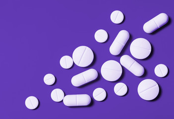 white tablets of various shapes on a bright purple background. Horizontal top view. Close-up