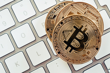 Gold coins of cryptocurrency bitcoin on a white keyboard