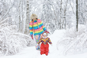 Fototapeta na wymiar small child and young mother in the winter outside in warm clothes fun