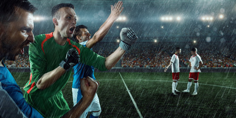 Soccer players and goalkeeper emotionally happy after victory. Players joyfully screaming on the...