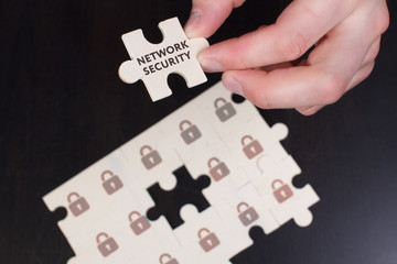 The concept of business, technology, the Internet and the network. A young businessman collects a puzzle with the proper inscription: Network security