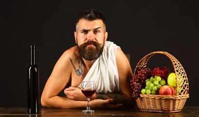 Man with beard holds glass of wine on brown background