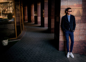 Obraz premium Man in black jacket and jeans leans to a marble wall