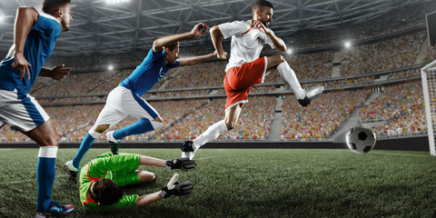 Soccer player scores the ball into the goal on professional stadium. The goalkeeper protects the...