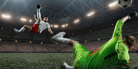 Soccer player scores the ball into the goal on professional stadium. The goalkeeper protects the football gate. Players wears unbranded sport uniform. © Alex