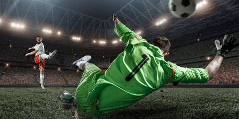 Soccer player scores the ball into the goal on professional stadium. The goalkeeper protects the...