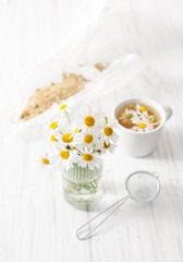 A bouquet of daisies and broth in a Cup on a white table