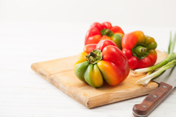 Three multi-colored peppers on a white table