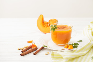 The juice of pumpkin in the bowl with the cinnamon and chopped pumpkin on white